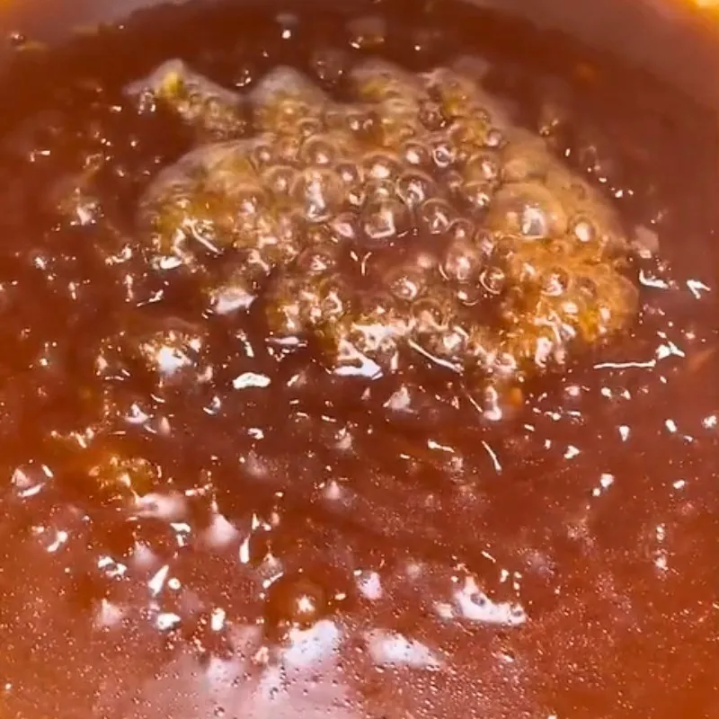 Đổ nước sốt me chua ngọt đã chuẩn bị vào chảo tôm đang xào